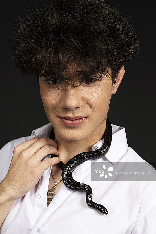 脖子上缠绕着黑蛇的年轻帅气男子图片素材