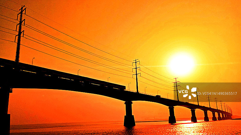 夕阳下，列车驶过孟加拉国的一座桥梁图片素材