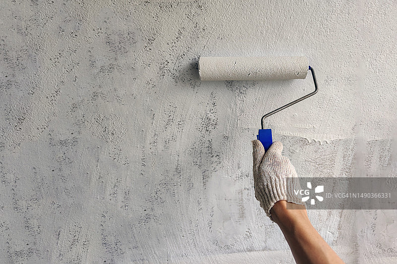 用滚筒在墙上刷白色油漆的女孩，特写镜头，有文案空间，俄罗斯图片素材
