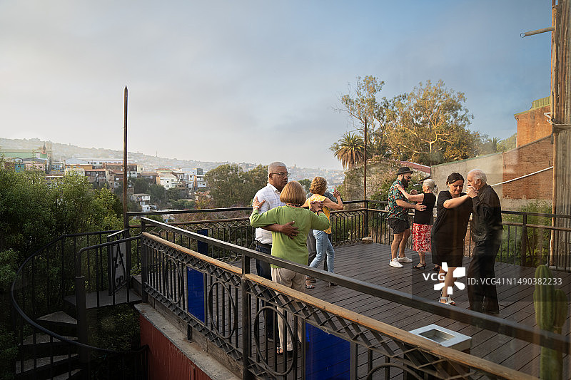 多对老年夫妇在俯瞰城市天际线的露台上一起跳舞图片素材