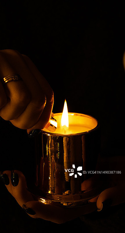 女子在黑暗房间手持点燃的蜡烛，俄罗斯圣彼得堡图片素材