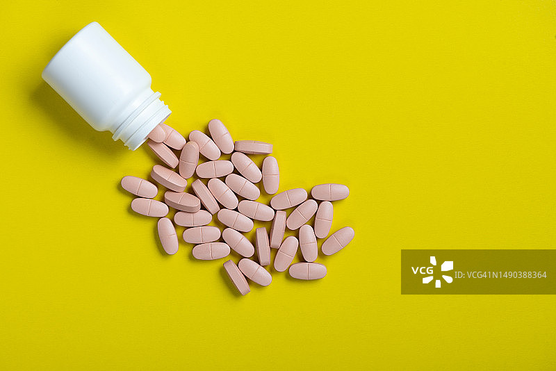 黄色背景上的药丸和药瓶，具有复制空间的宏观俯视图图片素材
