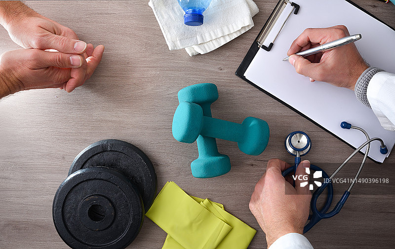 理疗师在诊桌上为患者记录，配备运动器材，西班牙图片素材