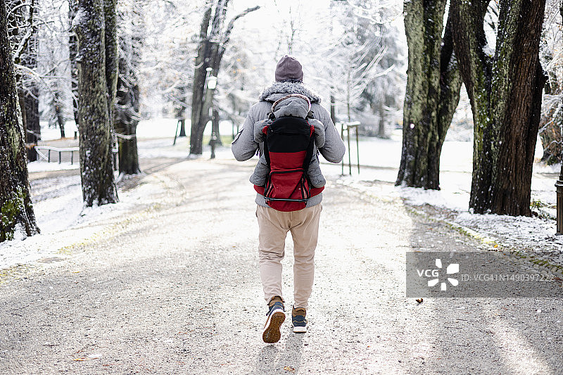 运动型父亲抱着穿着冬季连体衣和帽子的幼子图片素材