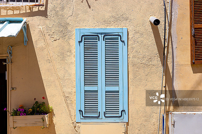 阳光下黄色墙壁上的蓝色百叶窗图片素材