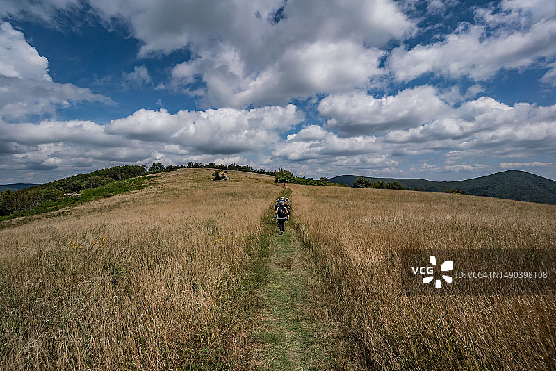 在美国弗吉尼亚州科尔山小径上，在多云天空下徒步旅行的男人们的背影图片素材