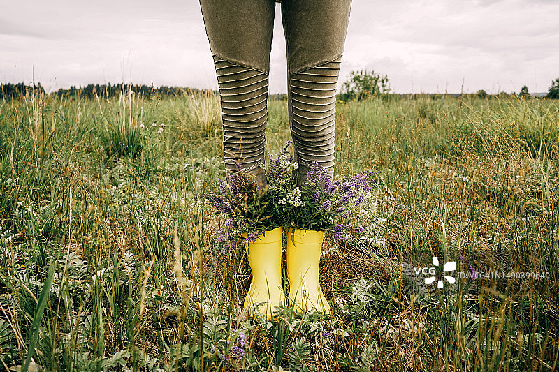 田野中带有野花的黄色雨靴图片素材