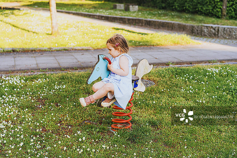 快乐小女孩在操场骑马图片素材