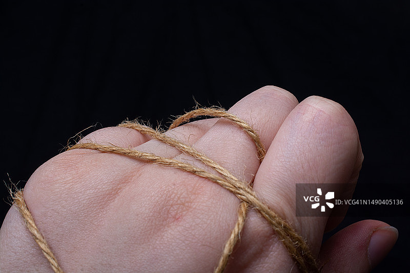 黑色背景下手持绳子的特写，土耳其图片素材