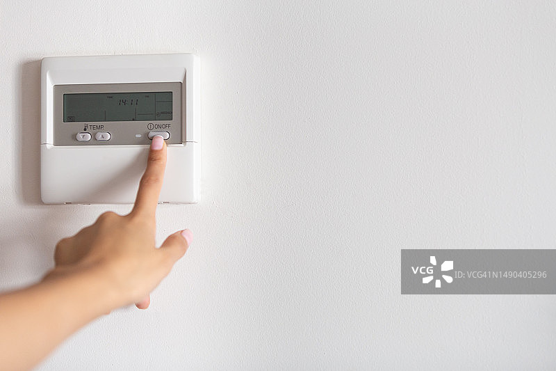 年轻女子的手按下空调或暖气开关的特写，西班牙马德里图片素材
