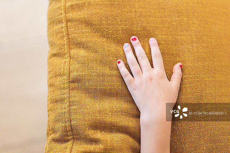 孩子坐在沙发上，指甲油涂得不好看图片素材