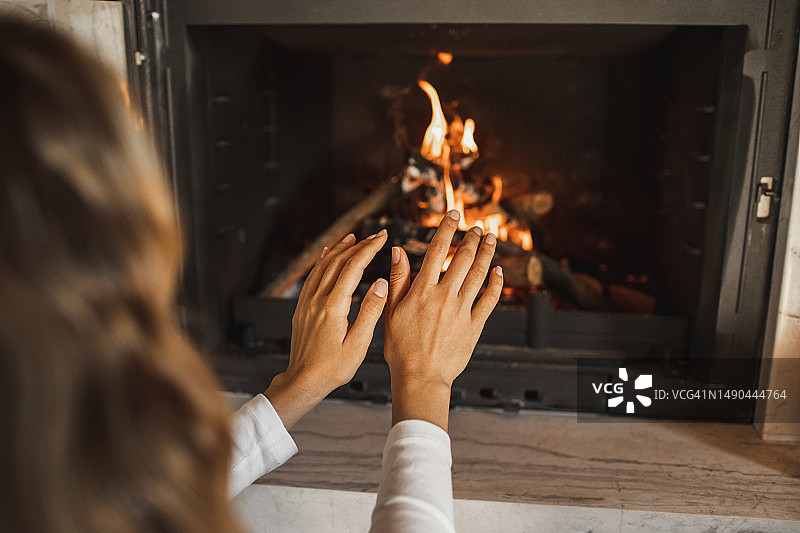 女子在壁炉旁暖手图片素材
