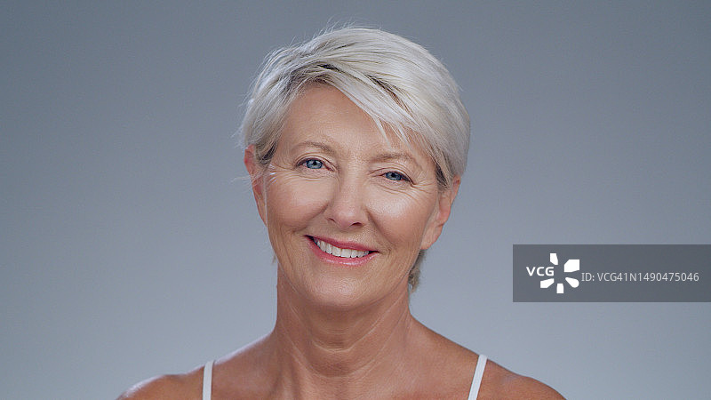 年长的白人女性的护肤写真，自信女士在灰色背景下的皮肤护理图片素材
