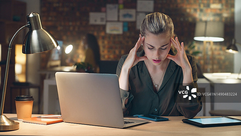 女商人，在办公室里，因倦怠、压力或加班而在夜间头痛和焦虑。压力大、疲惫或焦虑的女员工工作到很晚，并遭受严重的头部疼痛、酸痛或劳损图片素材