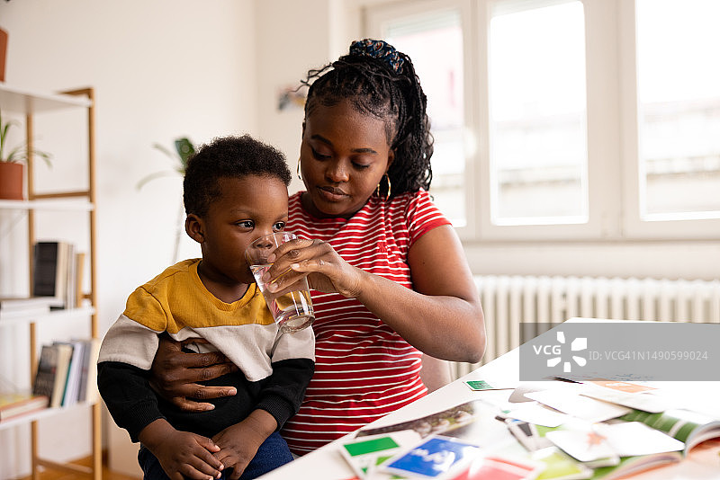 年轻的黑人母亲给儿子喂水图片素材