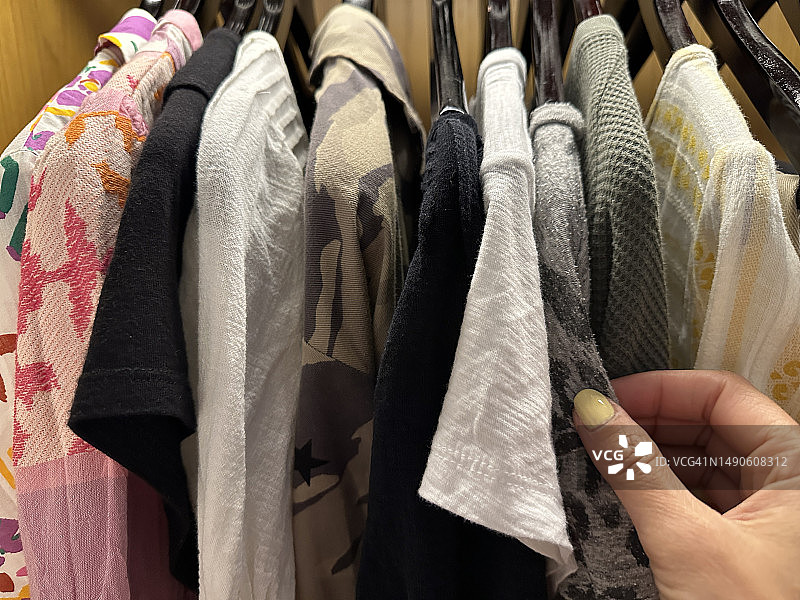 女人伸手去拿衣柜里挂着的上衣图片素材