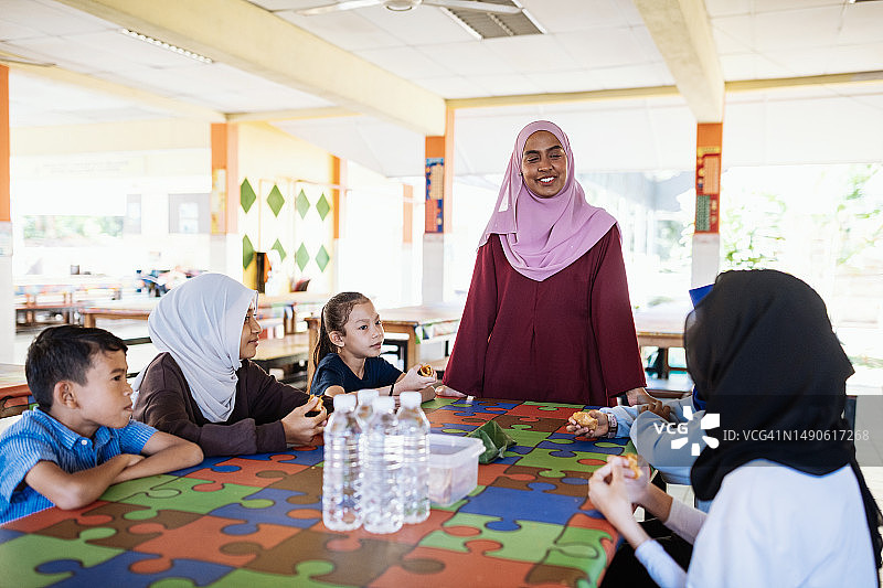 小学生和老师在食堂吃早餐，开心玩耍图片素材