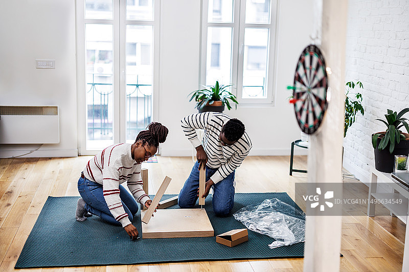 一对年轻的非裔美国夫妇正在组装新家具图片素材