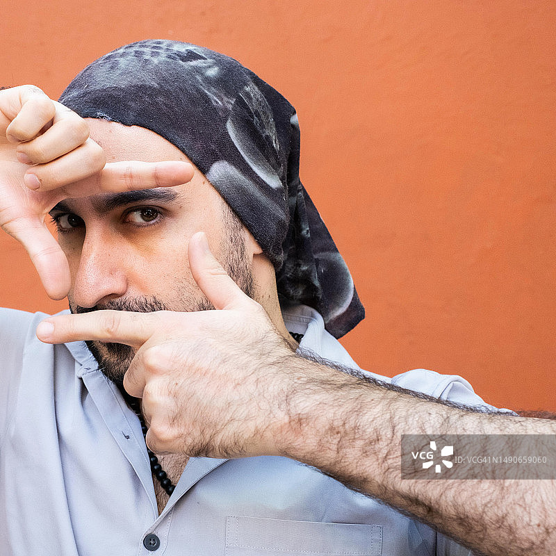 戴着头巾的中东裔拉丁美洲男子看着镜头，用手和手指取景图片素材