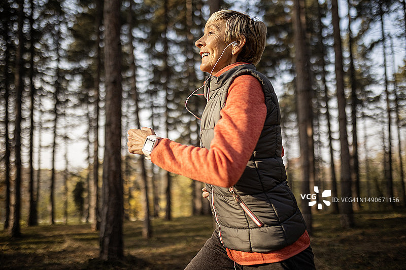 中年妇女戴着耳机在户外锻炼图片素材