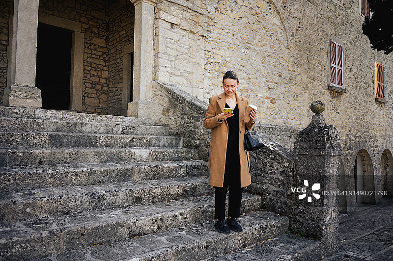 站在楼梯上的商务女性，手持手机图片素材