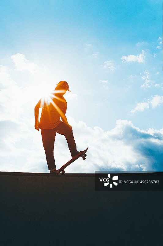 阳光明媚的日子里男性滑板运动员的轮廓图片素材