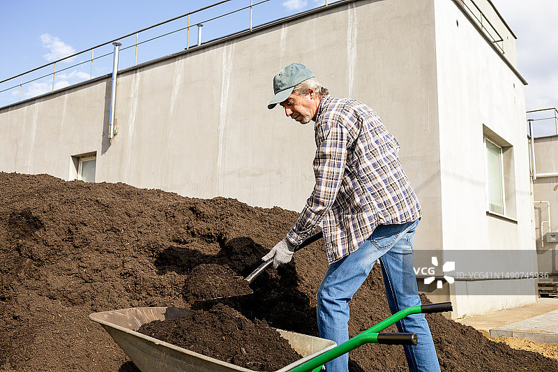 一位50岁的男性农民用铲子挖一堆有机肥料图片素材