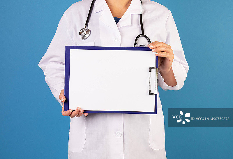 医生在蓝色背景前手持空白标语牌的中段视角照片，罗马尼亚图片素材