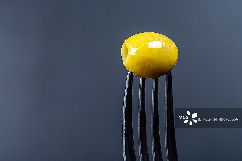 深色背景叉子上的腌制绿橄榄，罗马尼亚图片素材