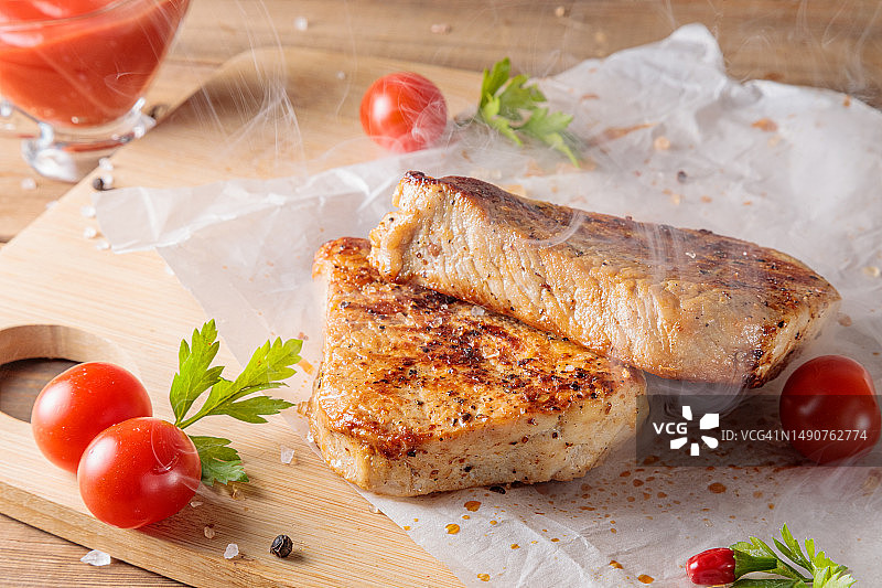 木板上放着搭配番茄酱的烤猪肉切片图片素材