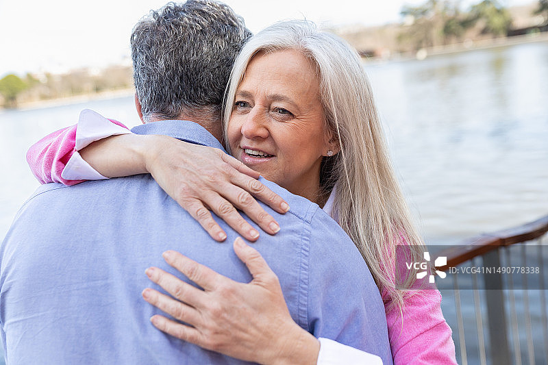 在公园里穿着休闲服装亲切拥抱微笑的两位年长者图片素材