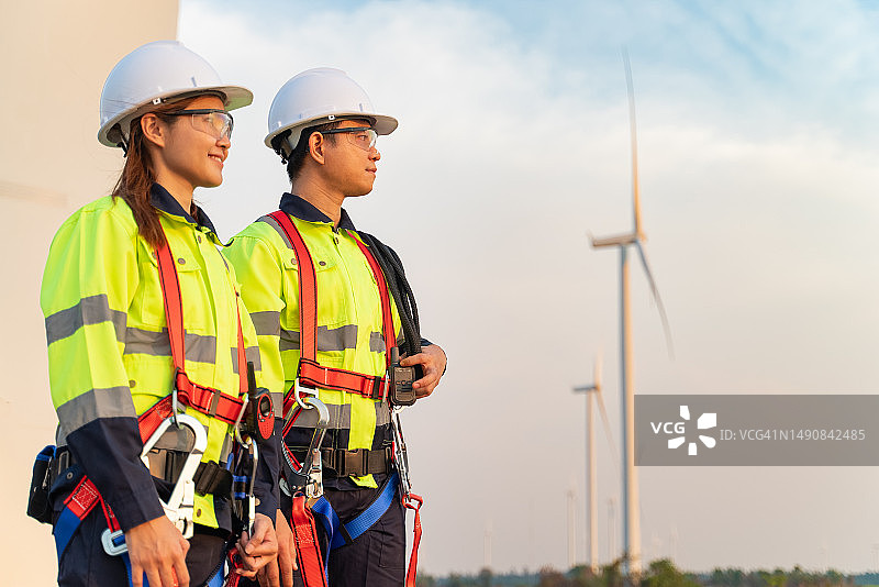 日落时分在风力涡轮机场工作的维护工程师团队图片素材