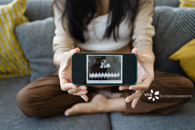 孕妇手持B超照片，腹部特写图片素材