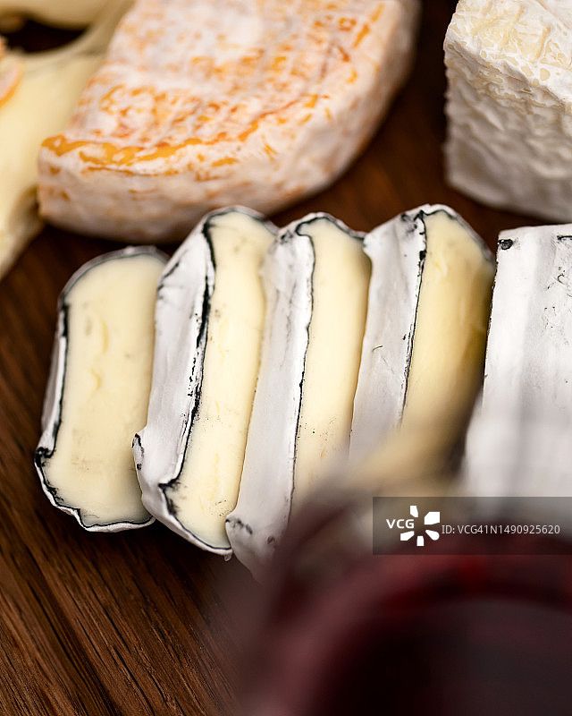 带木炭灰外壳和白色霉菌的软奶酪。奶酪头被切成薄片，卡门贝尔奶酪在桌子上。奶酪种类。木制背景。从上面看。柔和的焦点图片素材