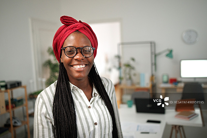 戴着非洲头巾、面带微笑的快乐黑人女性看着镜头图片素材