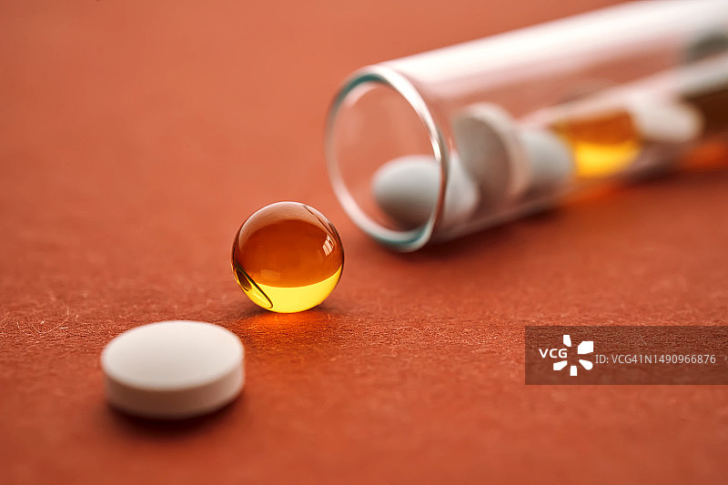 橙色背景试管中的药片、维生素和膳食补充剂图片素材