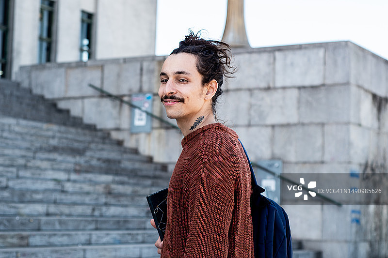 年轻男学生在户外拿着笔记本/教科书的肖像图片素材