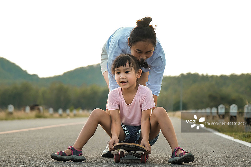 母亲在公园教女儿玩滑板，孩子玩滑板，健康运动，泰国图片素材