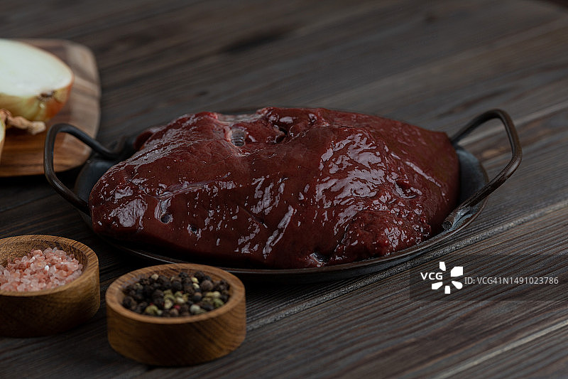木质背景上的金属盘生牛肉肝图片素材