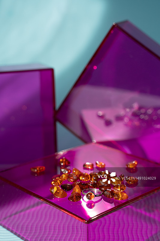 粉色玻璃台上琥珀戒指和宝石，法国图片素材