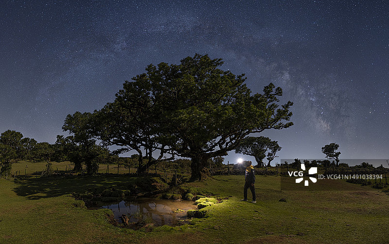 春夜，男人在葡萄牙马德拉群岛的法纳尔森林银河下图片素材