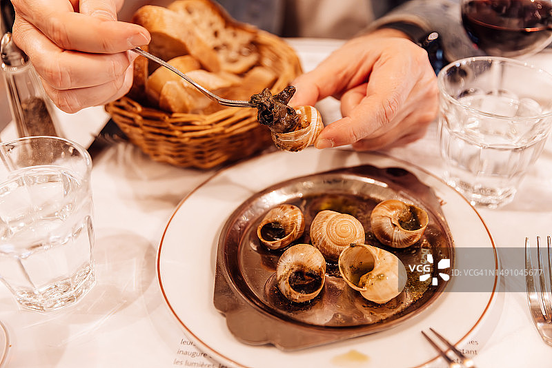 男人在法国巴黎的法国餐厅吃蜗牛图片素材