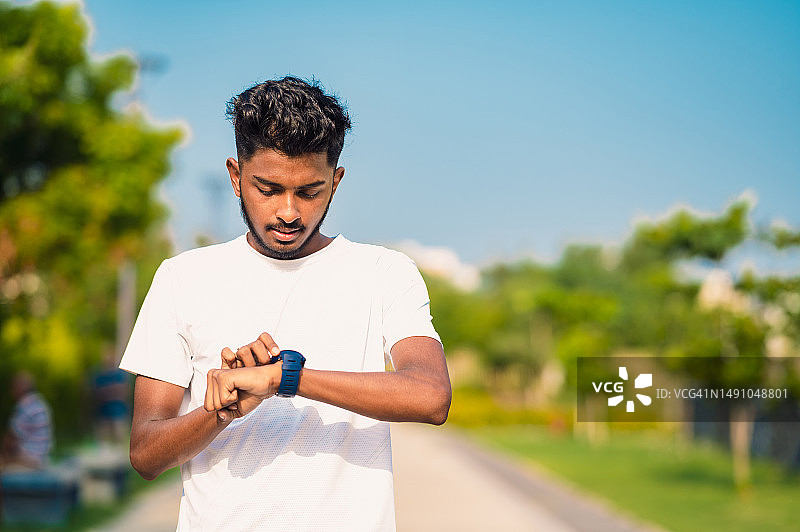 年轻运动男子在户外运动时查看手表特写图片素材