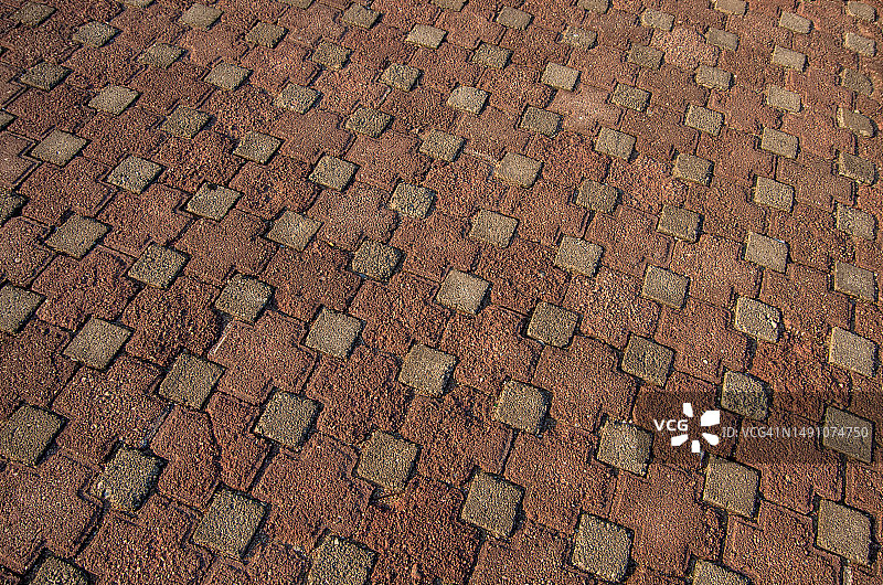 人行道上灰色小方块和红色大十字形状的互锁铺路石图片素材