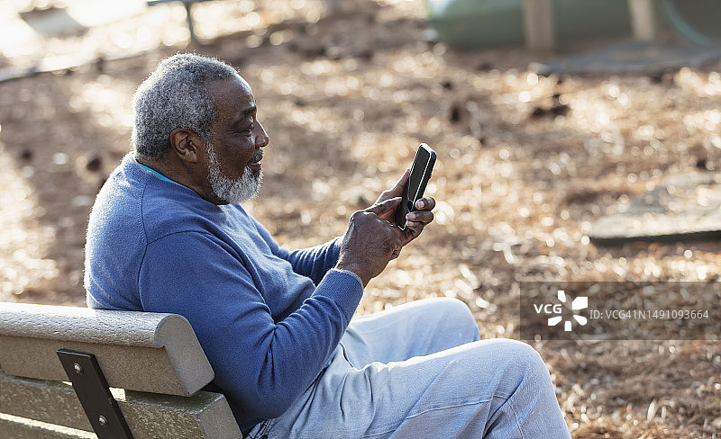 在公园使用智能手机的年长的非裔美国男人图片素材