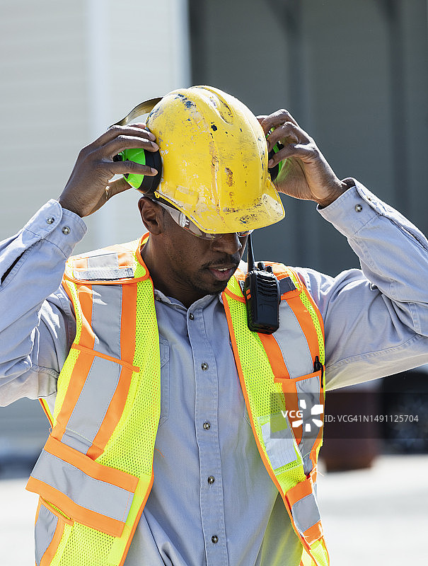 男子在建筑工地戴上耳罩图片素材
