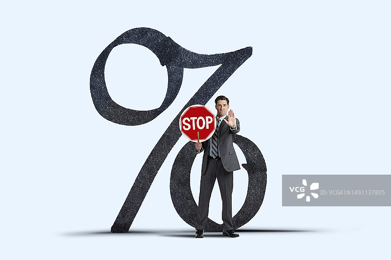 男人在一个大的百分比符号前举着停止标志图片素材