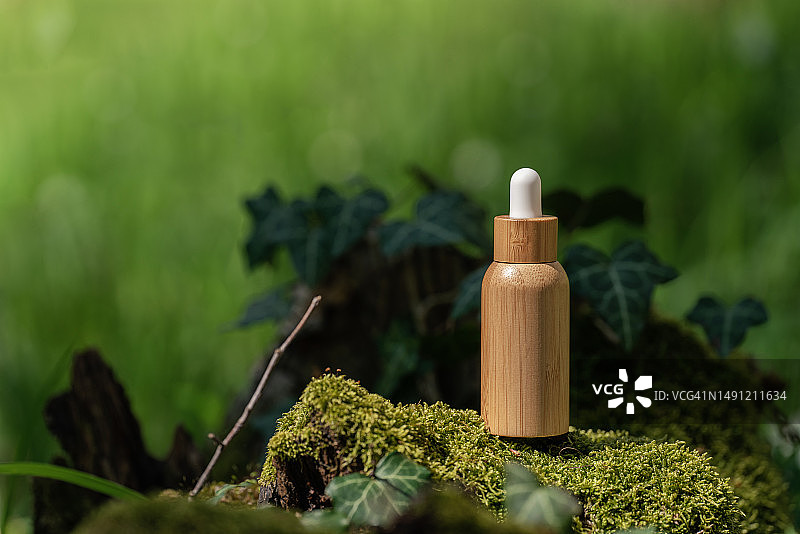 绿色森林背景下的竹制滴管精油瓶或精华液瓶图片素材