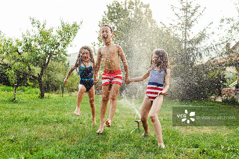 孩子们用花园洒水器降温图片素材