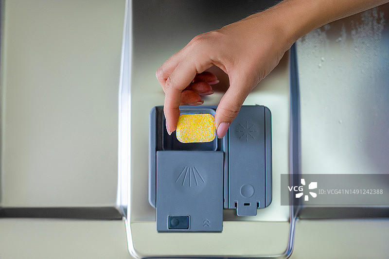 手将洗碗块放入洗碗机图片素材